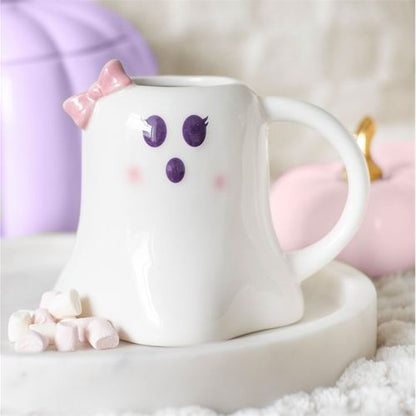 White mug with ghost face design on a white surface with pink and purple accents